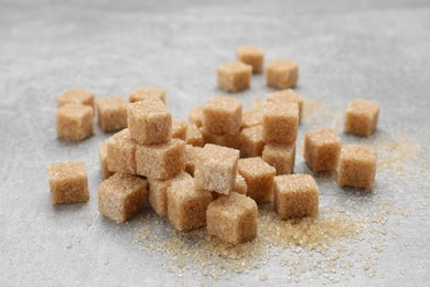 Many brown sugar cubes on grey table