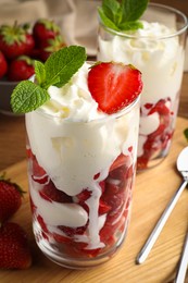 Photo of Delicious strawberries with whipped cream served on wooden table, closeup
