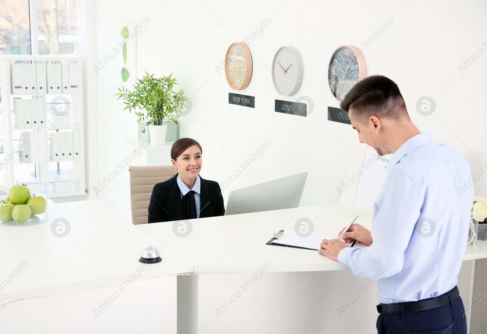 Photo of Young man filling form at reception desk in hotel