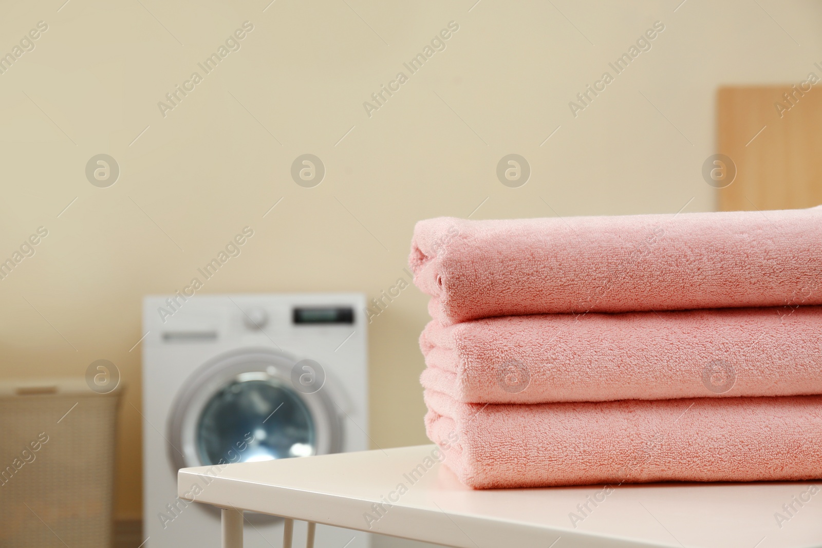 Photo of Stack of clean towels on table in laundry room. Space for text