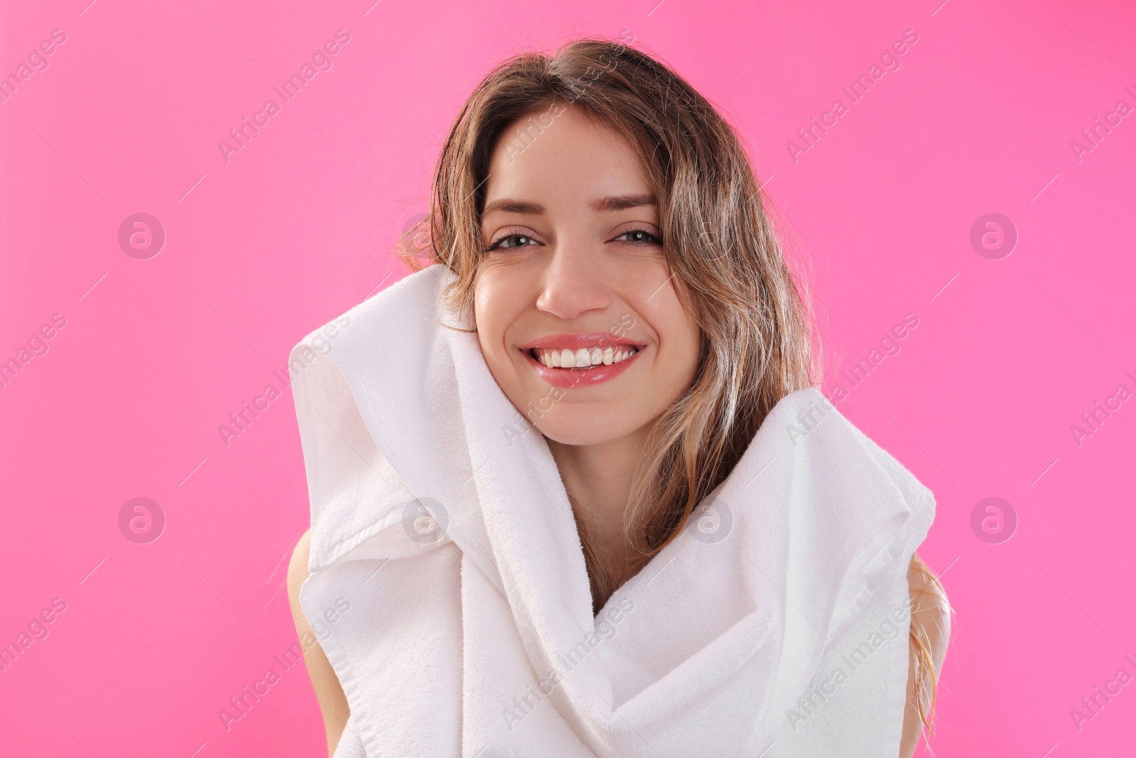 Photo of Beautiful young woman wiping hair with towel after washing on pink background