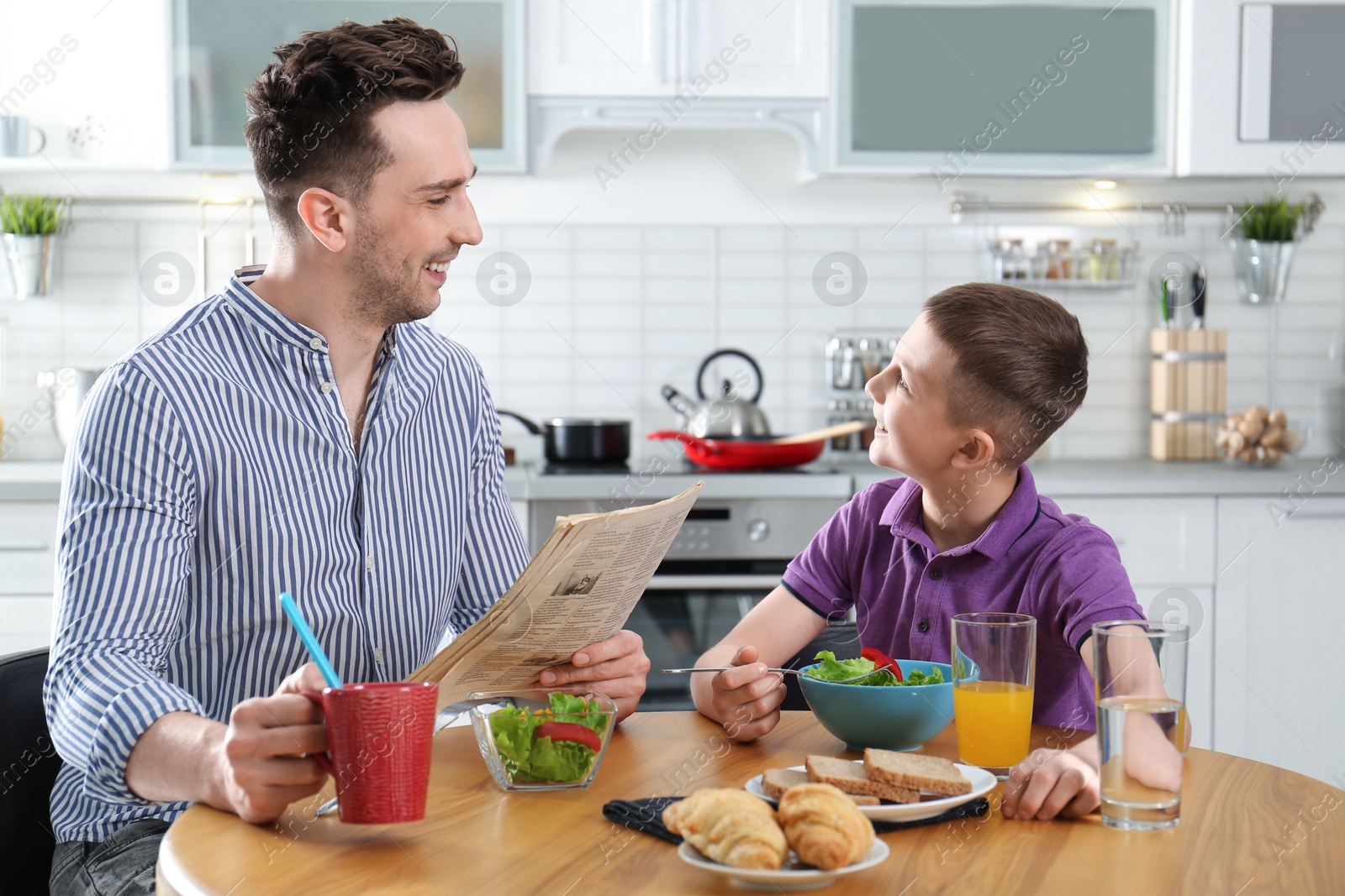 Photo of Dad and son having breakfast together in kitchen