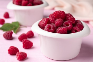 Photo of Bowl of delicious fresh ripe raspberries on pink wooden table, closeup view. Space for text