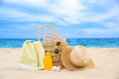 Different stylish beach objects and seashell on sand near sea