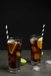 Photo of Refreshing soda drinks with straws on grey table against black background, space for text