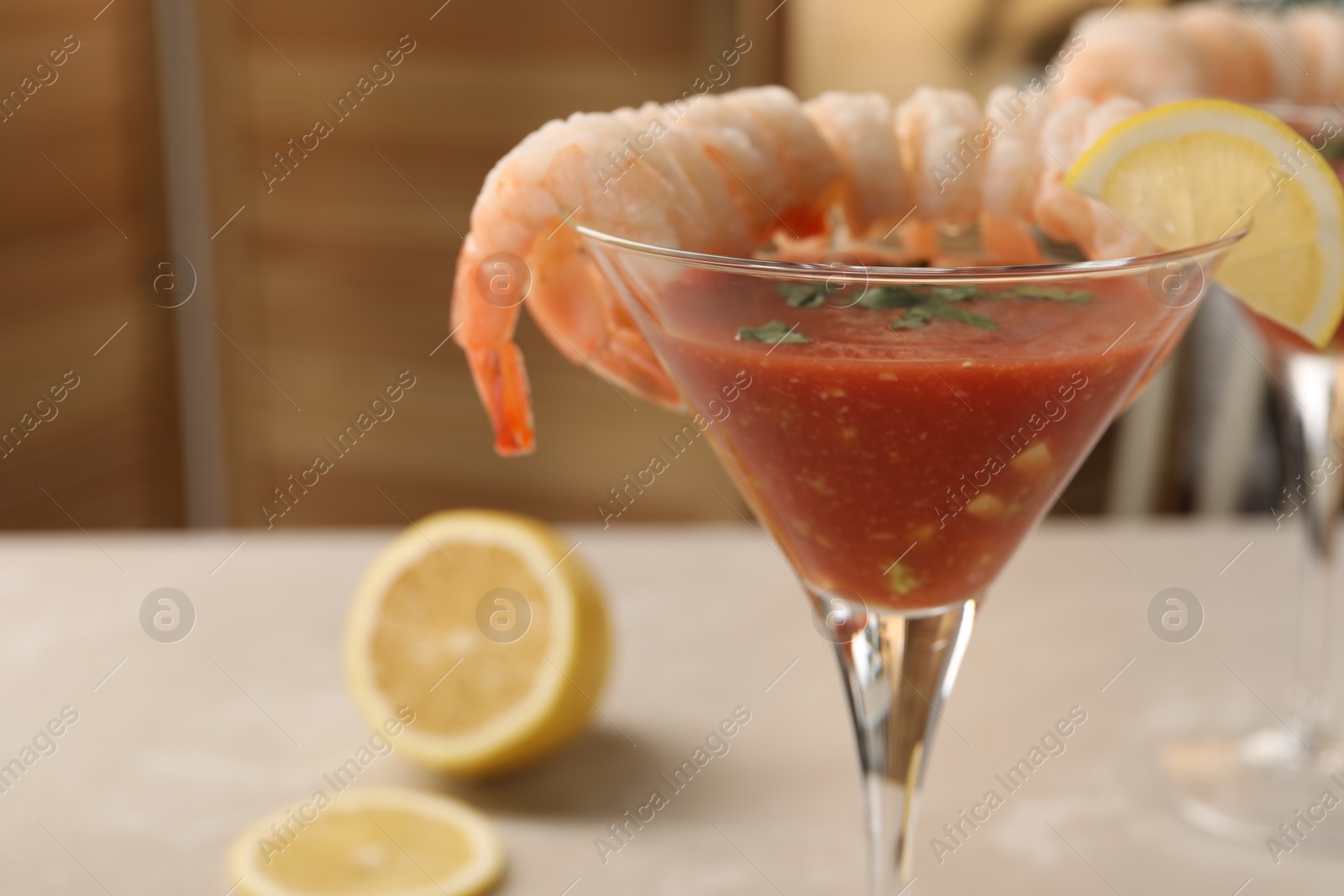 Photo of Tasty shrimp cocktail with sauce in glass and lemon on light table, closeup and space for text