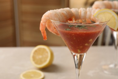 Photo of Tasty shrimp cocktail with sauce in glass and lemon on light table, closeup and space for text