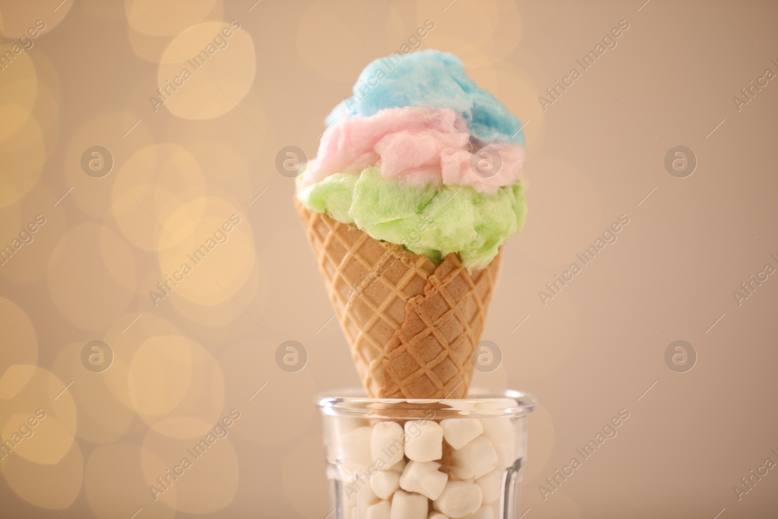 Photo of Sweet cotton candy in waffle cone against blurred lights, closeup