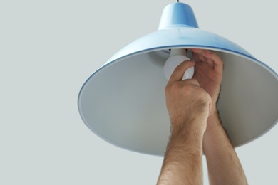 Man changing light bulb in lamp on white background, closeup