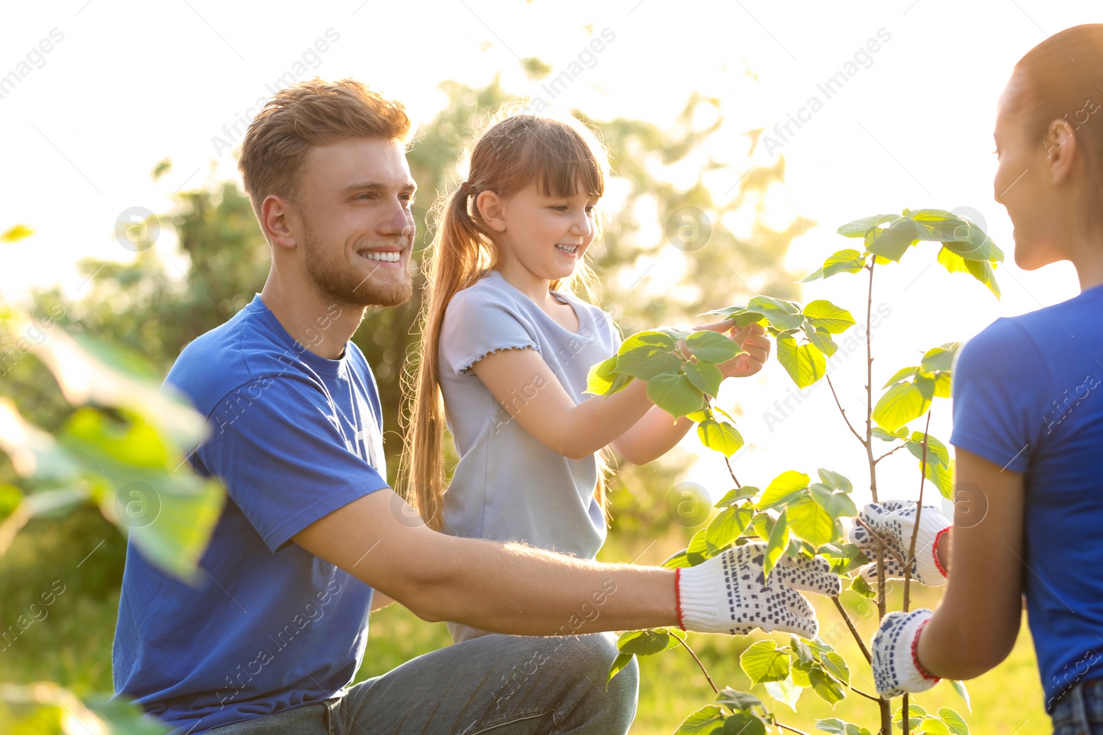 Photo of Little girl planting tree with volunteers in park