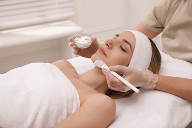 Photo of Young woman during face peeling procedure in salon