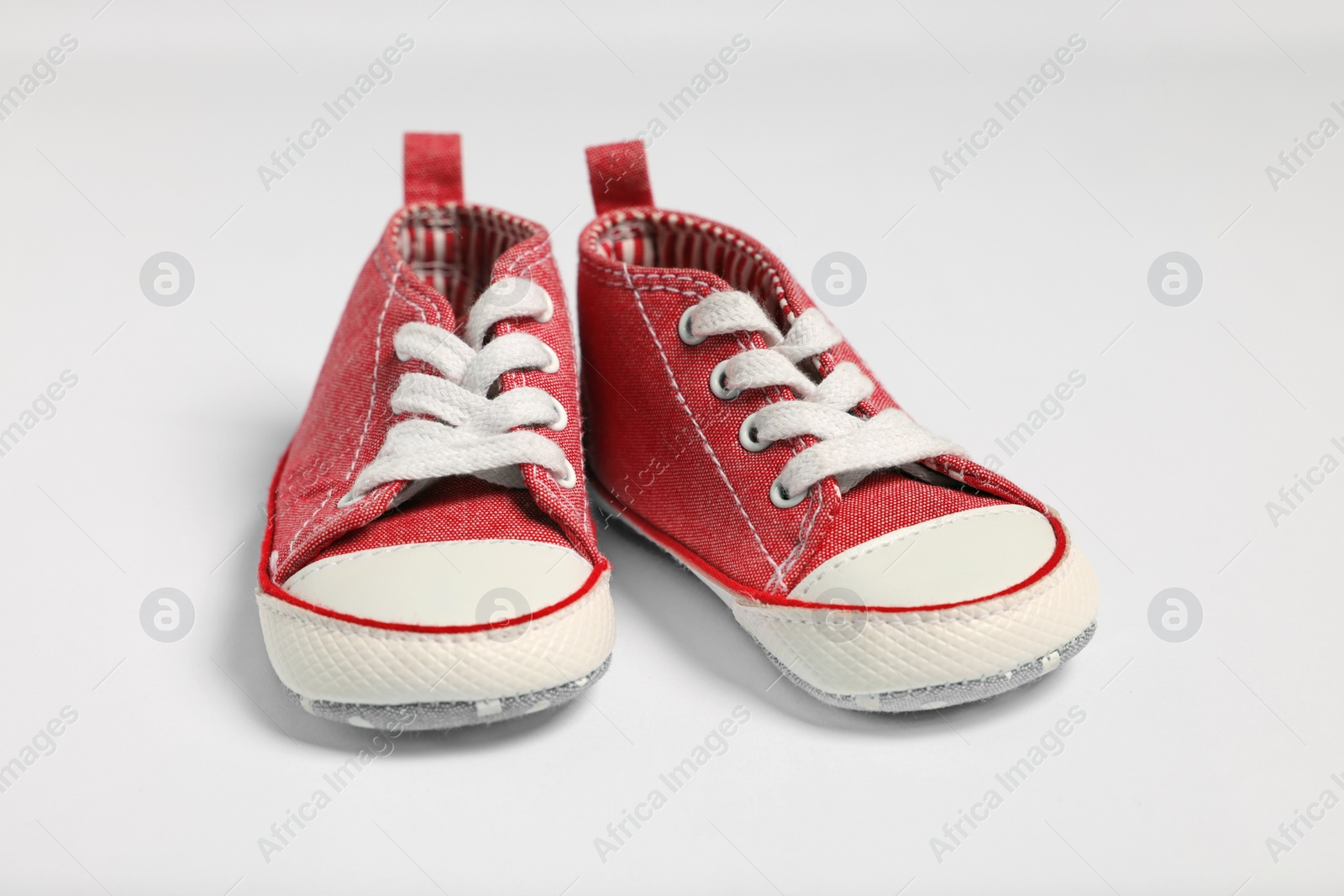 Photo of Pair of cute baby shoes on white background