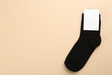 Pair of black cotton socks on beige background, top view. Space for text