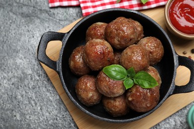 Tasty cooked meatballs with basil served on grey table, flat lay