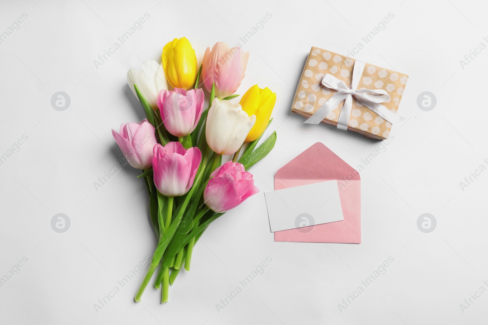 Photo of Flat lay composition of tulips and blank card on white background, space for text. International Women's Day