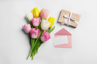 Flat lay composition of tulips and blank card on white background, space for text. International Women's Day