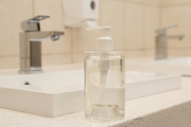 Photo of Dispenser bottle with antiseptic gel in public bathroom