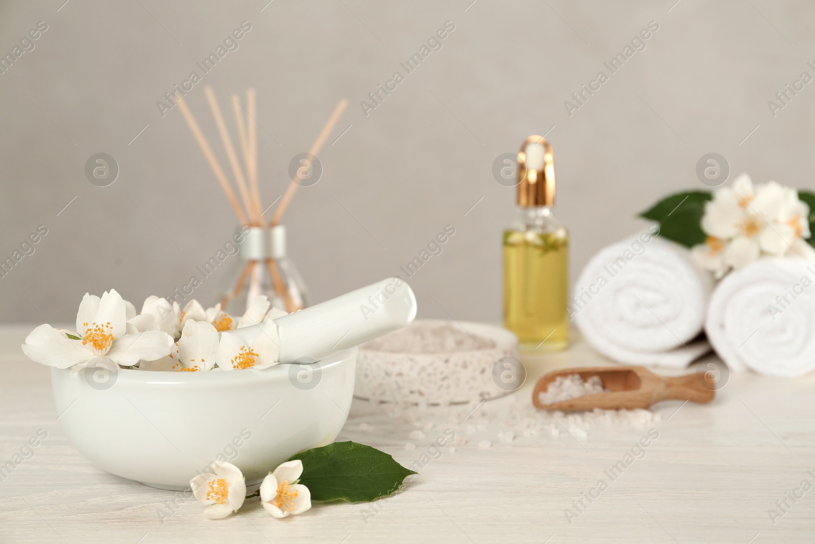 Photo of Mortar with beautiful jasmine flowers and pestle on white wooden table