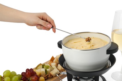 Photo of Woman dipping walnut into fondue pot with melted cheese on white background, closeup