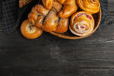 Photo of Different delicious fresh pastries on dark wooden background, flat lay. Space for text