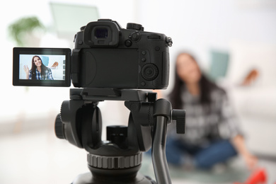 Photo of Young blogger recording video at cafe, focus on camera screen