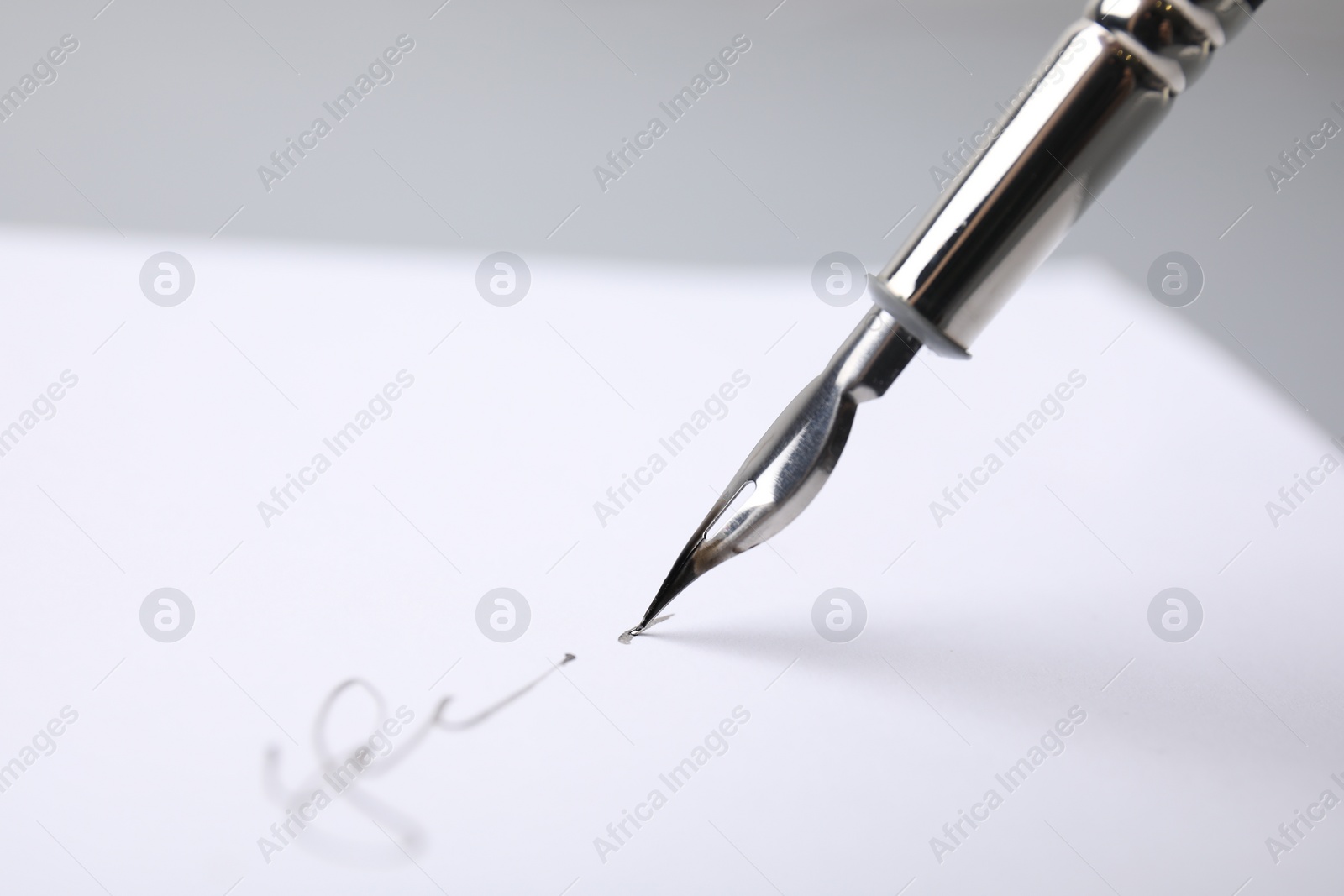 Photo of Signing on sheet of paper with fountain pen against light grey background, closeup. Space for text