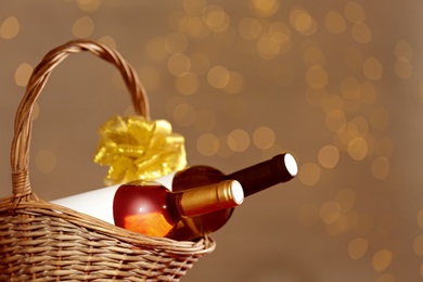 Photo of Bottles of wine in wicker basket with bow against blurred lights