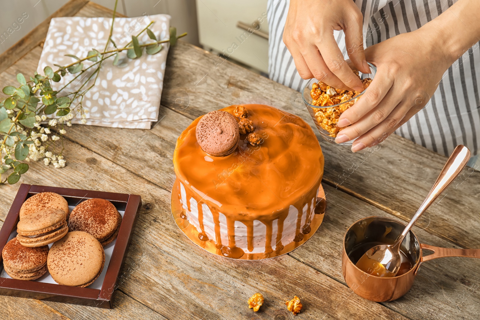 Photo of Young woman decorating delicious caramel cake at table