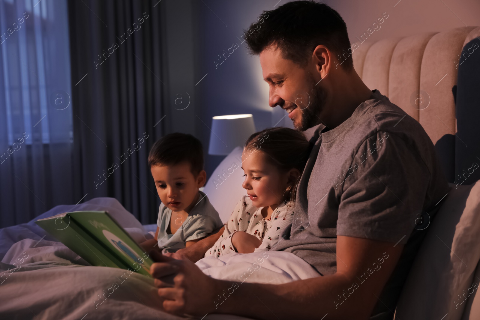 Photo of Father reading bedtime story to his children at home