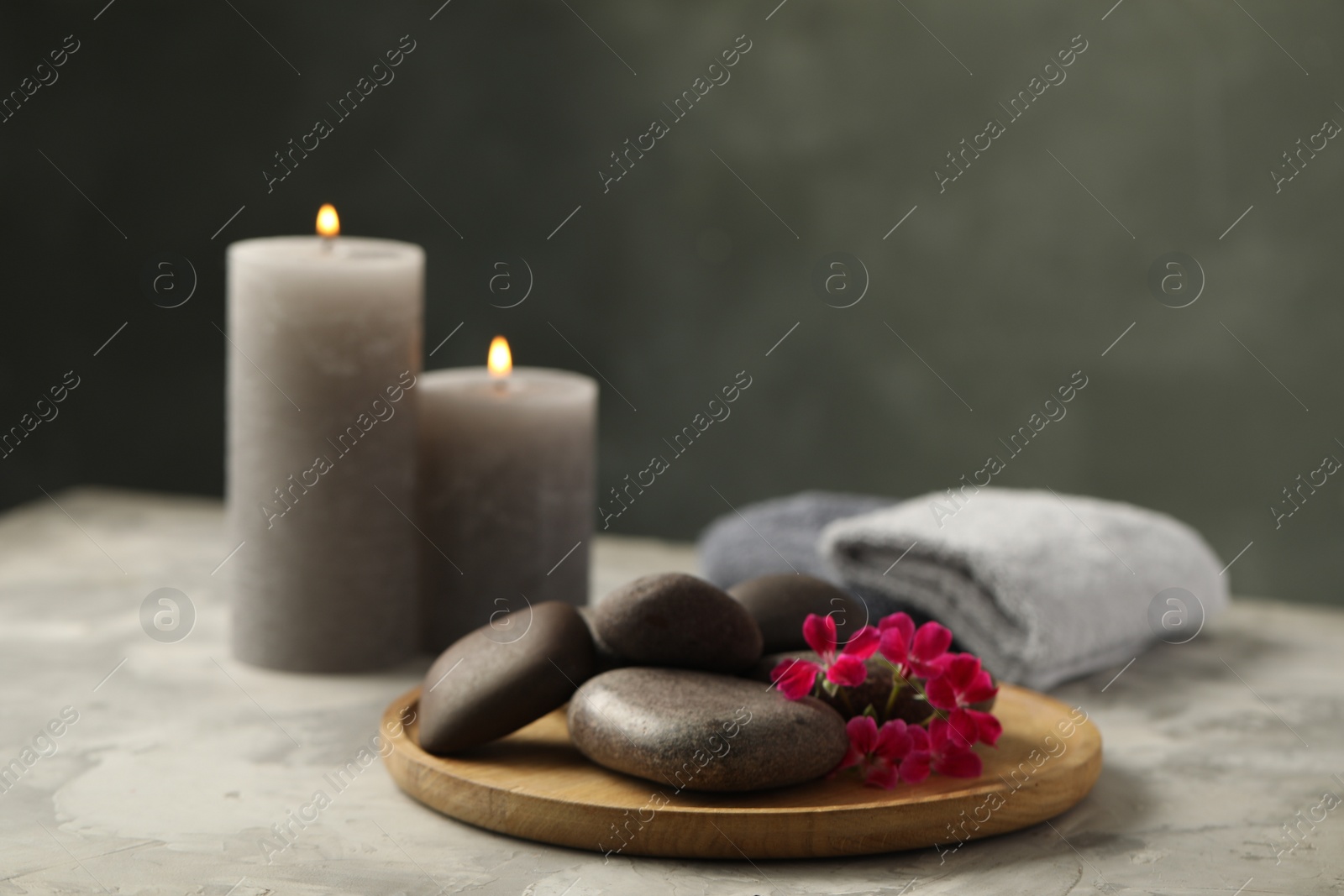 Photo of Spa stones and red flowers on grey table