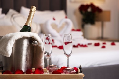 Honeymoon. Sparkling wine and glasses on wooden table in room