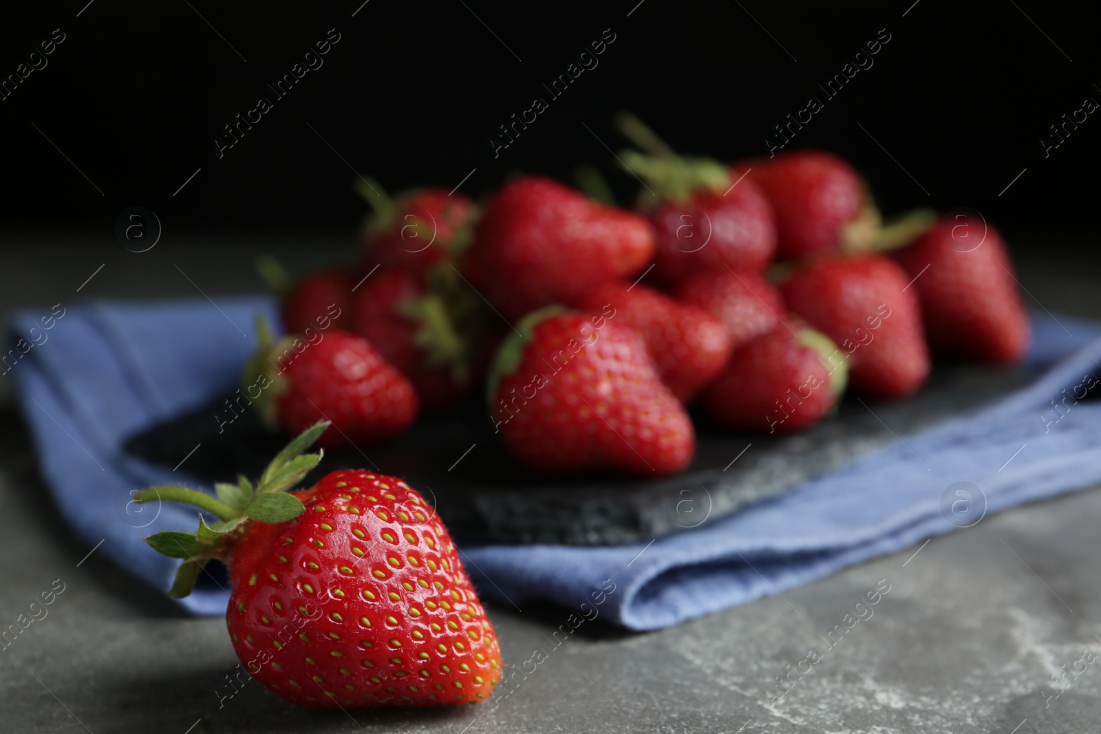 Photo of Many delicious ripe strawberries on grey table