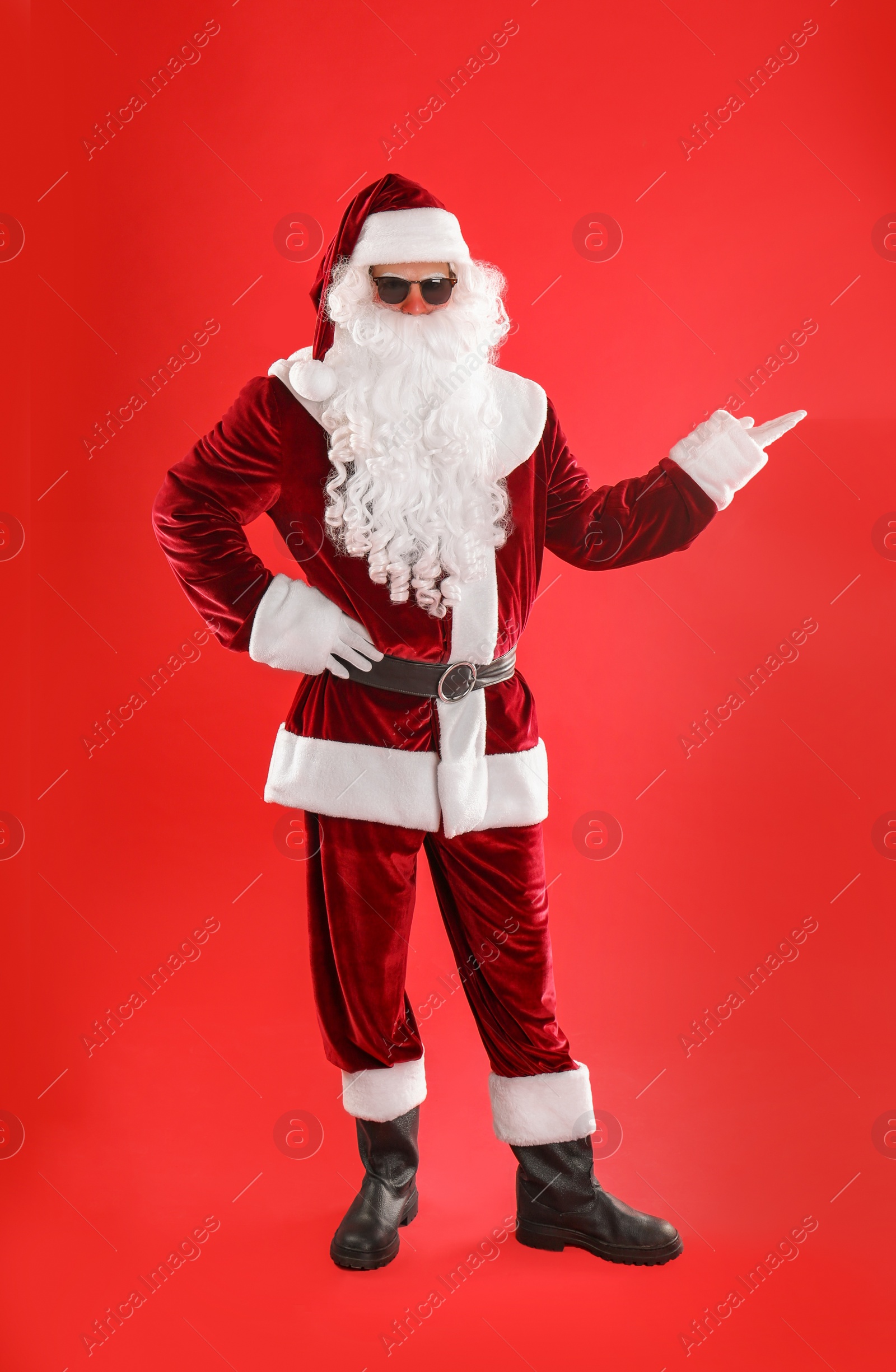 Photo of Full length portrait of Santa Claus with sunglasses on red background