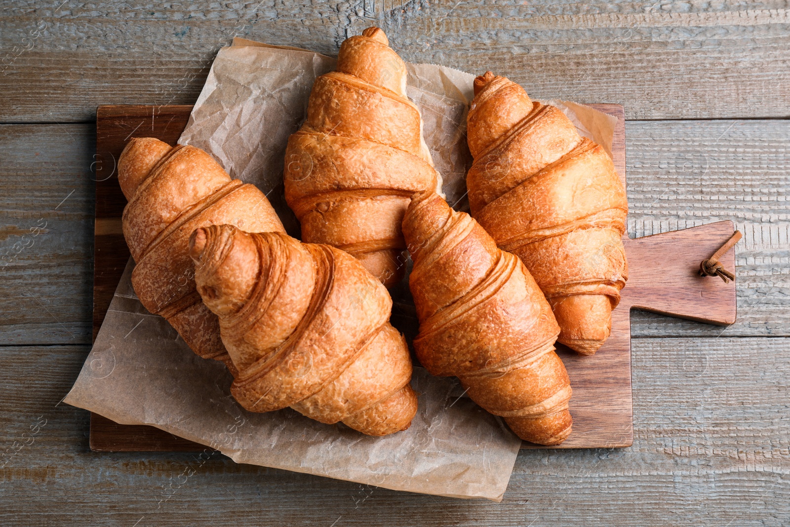 Photo of Tasty fresh croissants on wooden table, top view