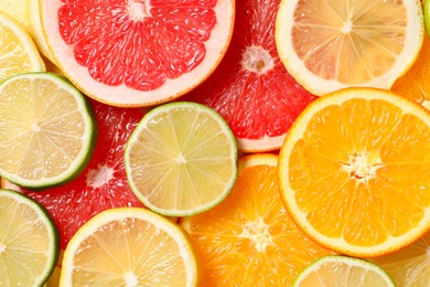 Photo of Different sliced citrus fruits as background, top view