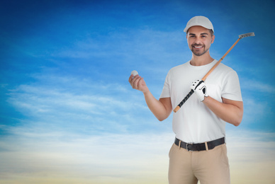 Young man with golf club and ball against blue sky. Space for design