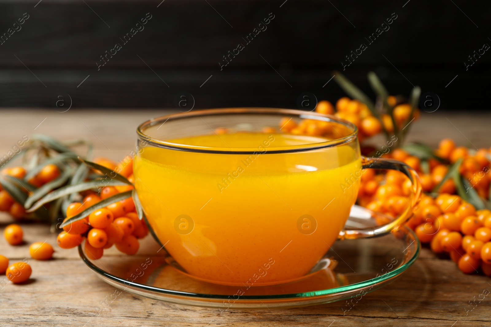 Photo of Fresh sea buckthorn tea on wooden table, closeup