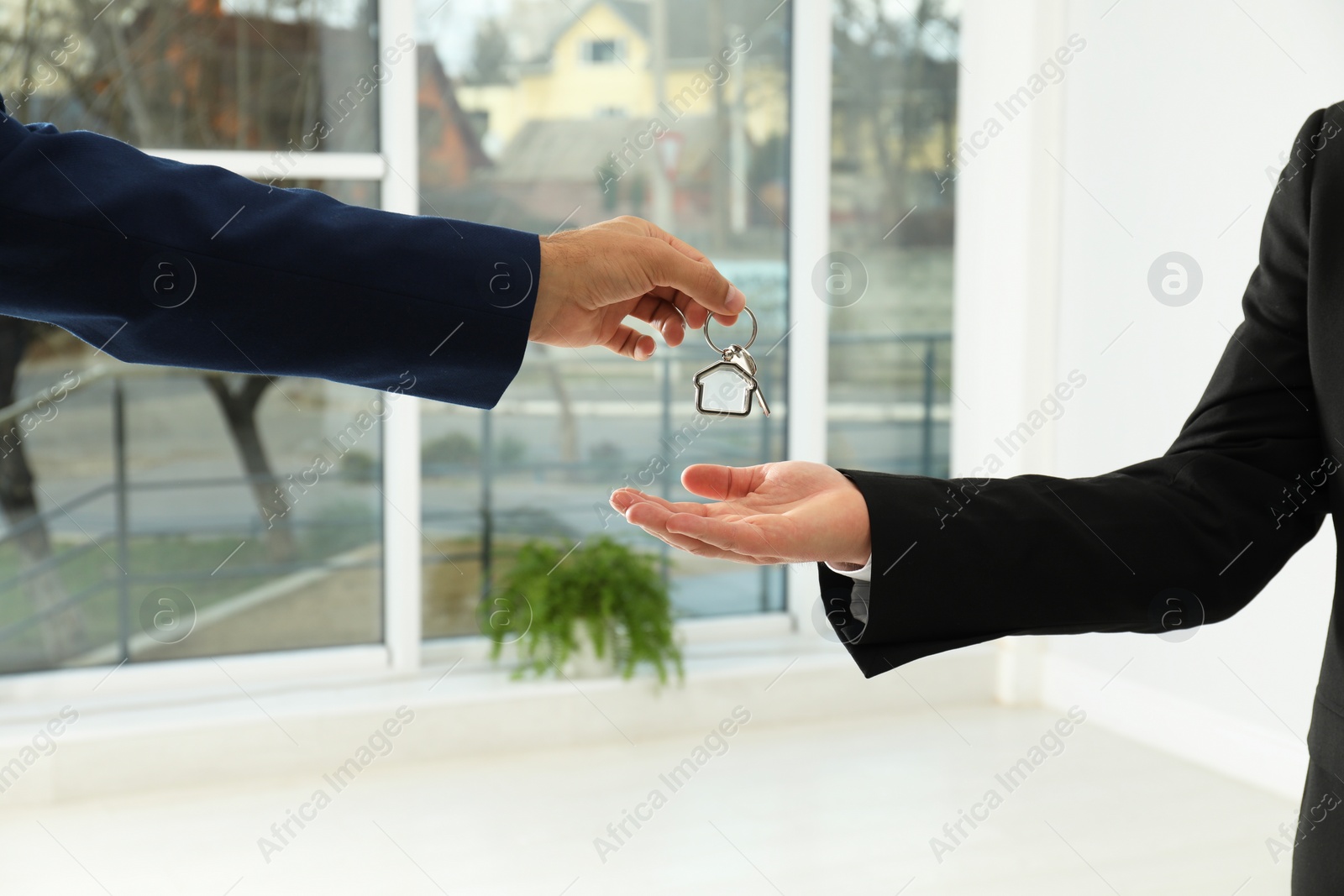 Photo of Real estate agent giving key to client in new house, closeup