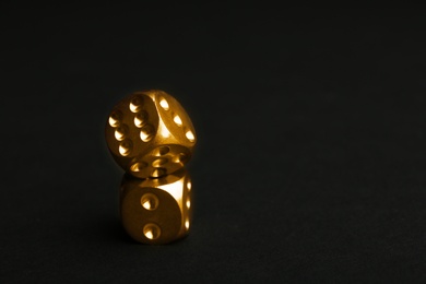 Photo of Stacked gold dices on black background. Space for text