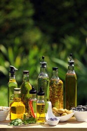 Photo of Different cooking oils and ingredients on wooden table against blurred green background