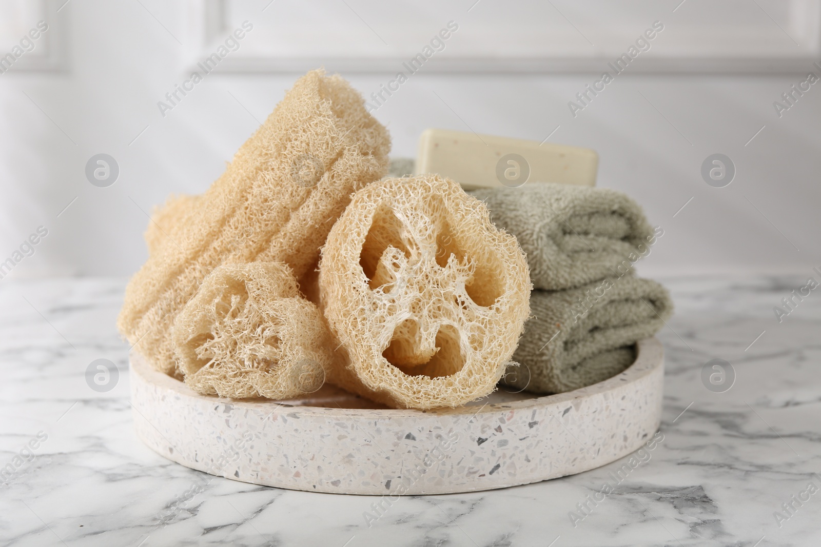 Photo of Loofah sponges, towels and soap on white marble table