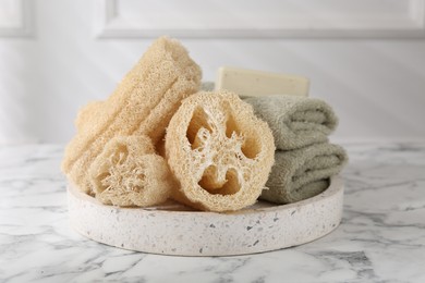 Loofah sponges, towels and soap on white marble table