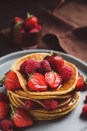 Photo of Tasty pancakes with fresh berries and honey on plate, closeup