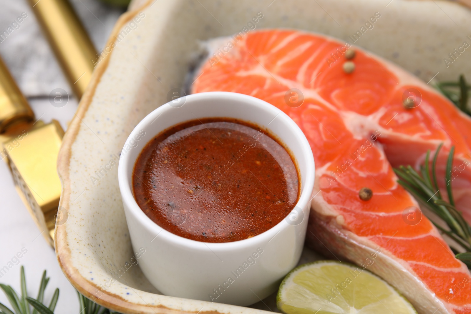 Photo of Fresh marinade, fish and lime in baking dish on table, closeup