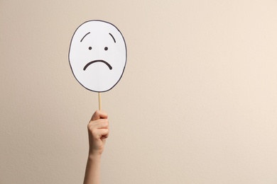 Photo of Woman with sad paper face on beige background, closeup. Space for text