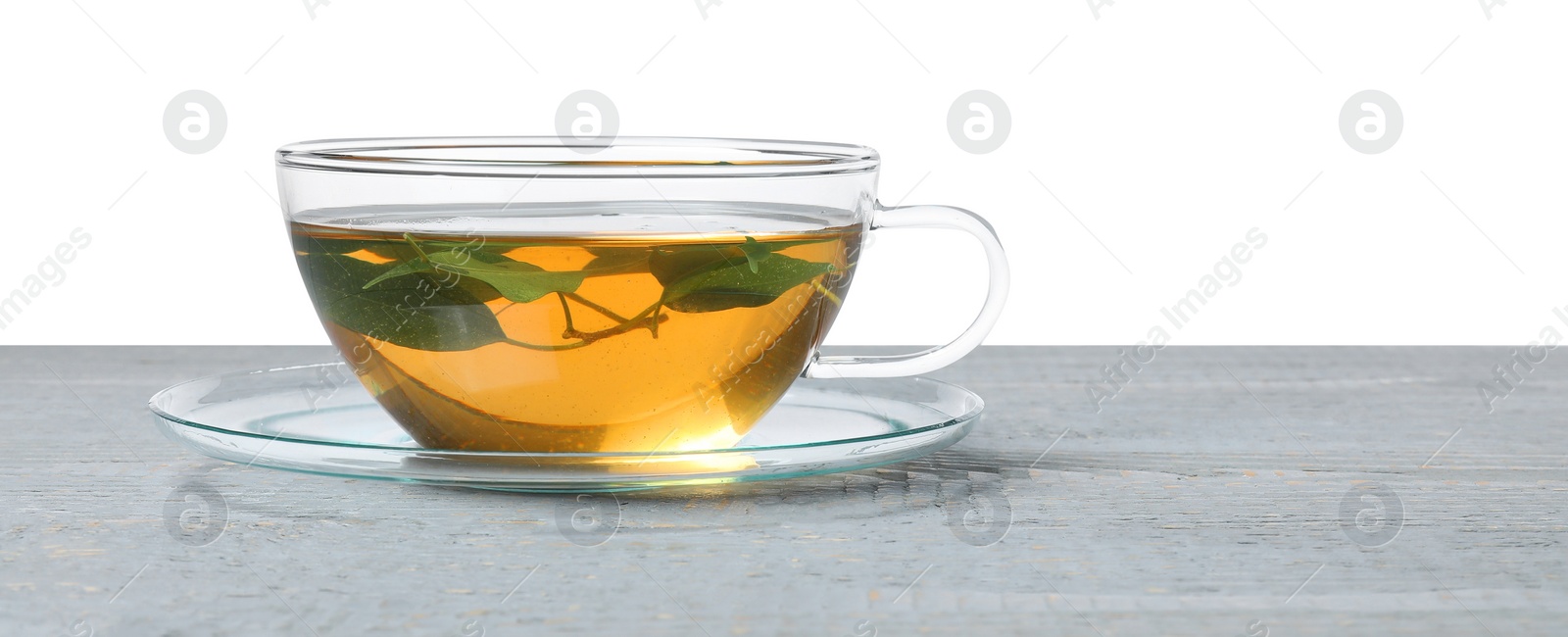 Photo of Refreshing green tea in cup on grey wooden table against white background