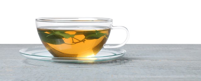 Refreshing green tea in cup on grey wooden table against white background