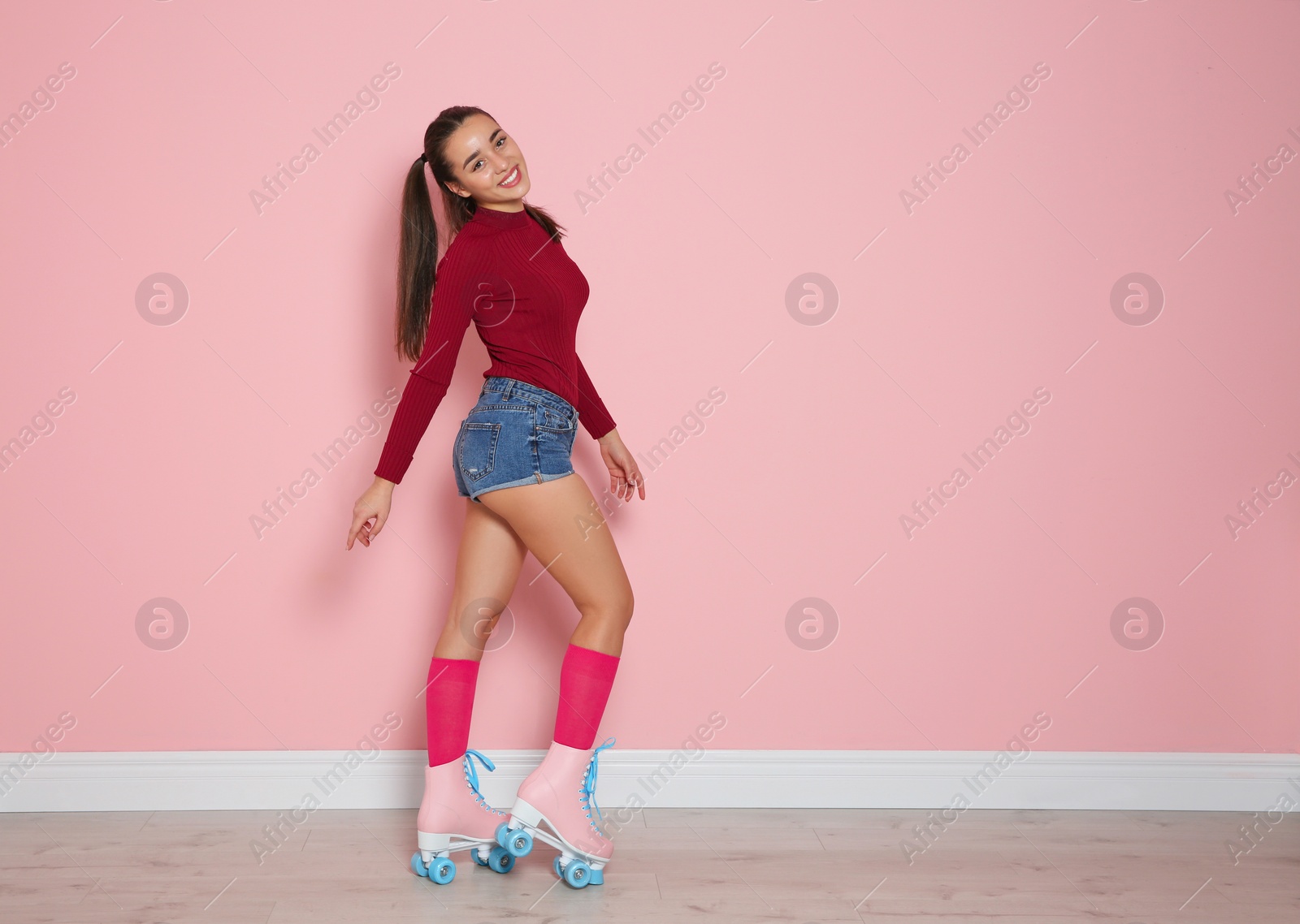 Photo of Young woman with roller skates near color wall. Space for text