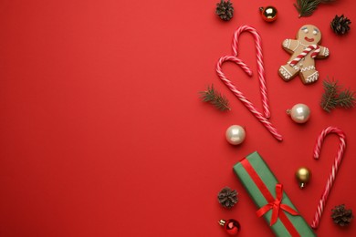 Photo of Flat lay composition with sweet candy canes and Christmas decor on red background, space for text