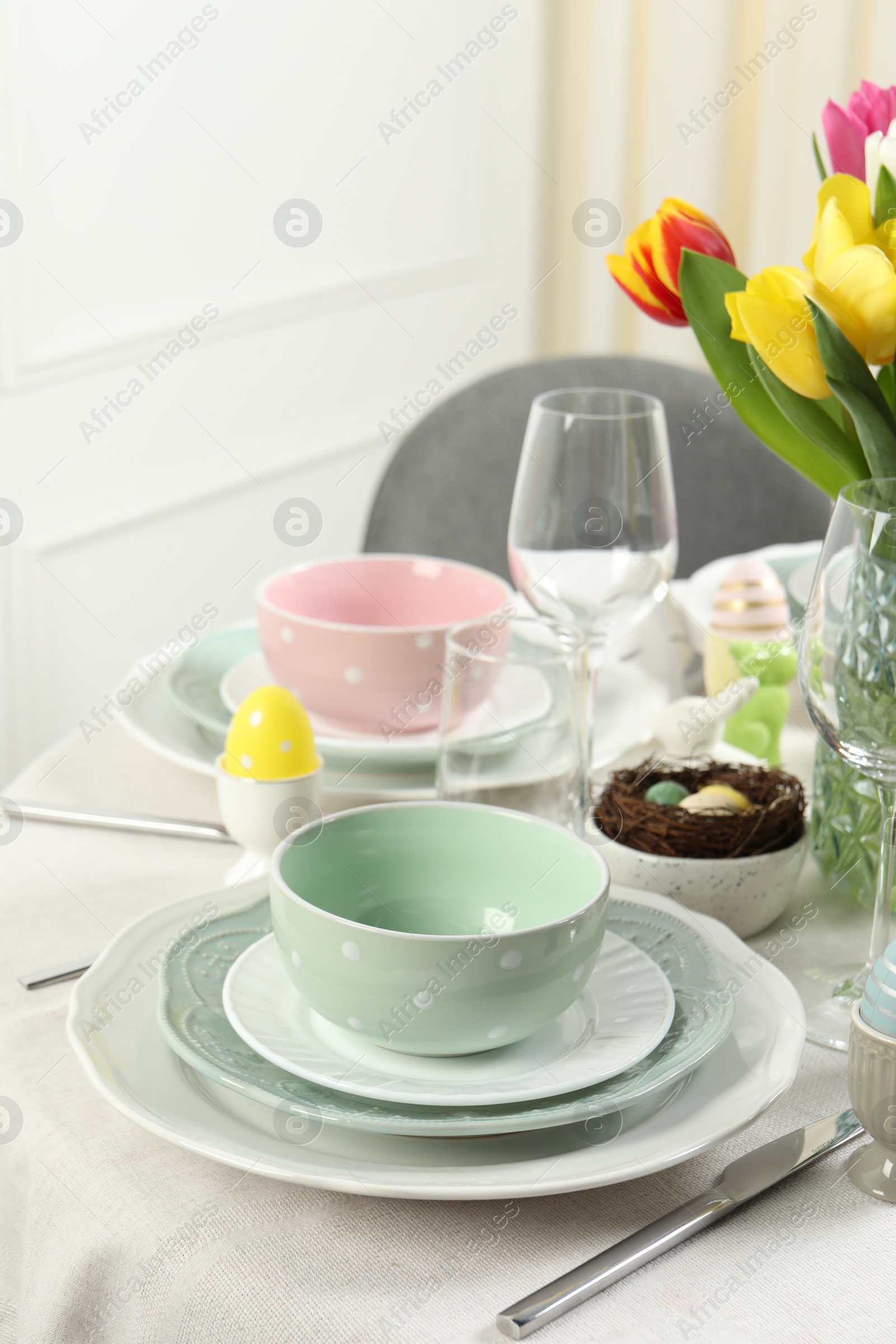 Photo of Easter celebration. Festive table setting with elegant dishware and painted eggs